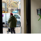Older women with walker at entrance of her apartment building.