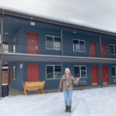 Woman standing infront of transitional housing. 