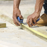 Construction worker measuring timber 