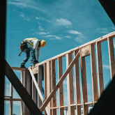 Man in hard hat working on top of wall.