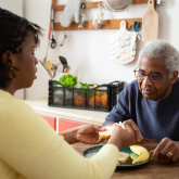 Man having a meal at home with a caregiver.