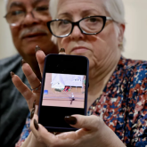 Woman holding up phone showing image of a flood.