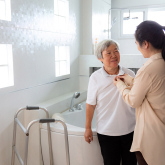 Caregiver helping older adult get dressed.