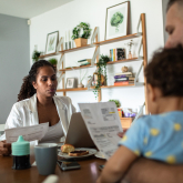 Hispanic couple with baby sitting at table reviewing bills.