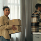 Two people moving boxes out of a home.