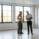 Young couple with a realtor in an empty home.