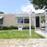 Small home with for sale sign in front.