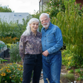 Two older adults standing in a garden.