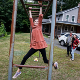 Parents watching as girl plays in yard outside their home.
