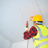 Worker installing drywall in a home.