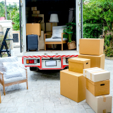 Moving truck and boxes in a driveway.