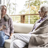 Two women sitting on a couch talking.