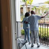 Older adult couple outdoors on apartment patio.