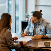 Man signing lease paperwork in realtor's office.