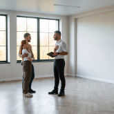 Couple standing in empty apartment with realtor.