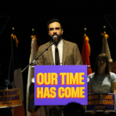 Zohran Mamdani speaking at a podium.