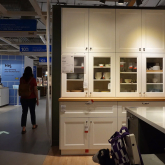 People walking past kitchen display in a furniture store.