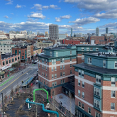 View of buildings lining Massachusetts Ave in Central Square, Cambridge, with Boston skyline in the distance..