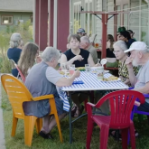 Group of older adults sharing a meal outdoors.