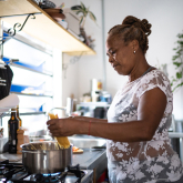 Older adult woman cooking dinner at home.