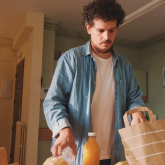 Man unpacking groceries in apartment kitchen.