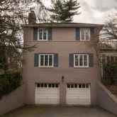 A stucco colonial home surrounded by trees.