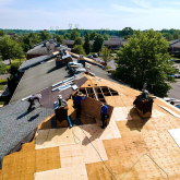 Workers installing roofing on a multifamily building.