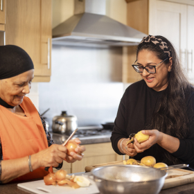 Older and younger woman cooking together in a kitchen.