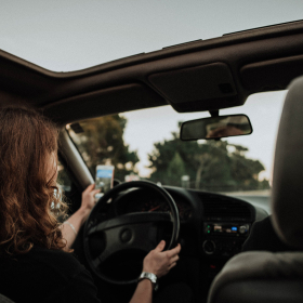 Woman driving a car and looking at her cell phone