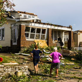 People outside a damaged home.