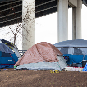 Tent encampment under an overpass.
