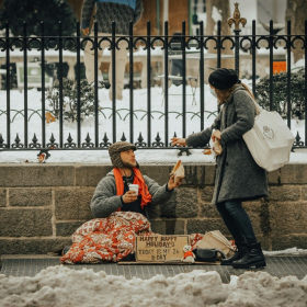 Person handing food to person on sidewalk.