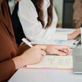 Students taking notes at a conference room table.