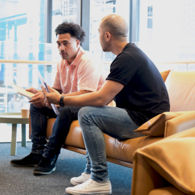 Two young men sitting in an office reception area.