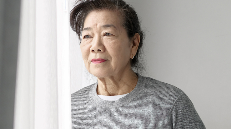 Older Asian woman looking out a window.