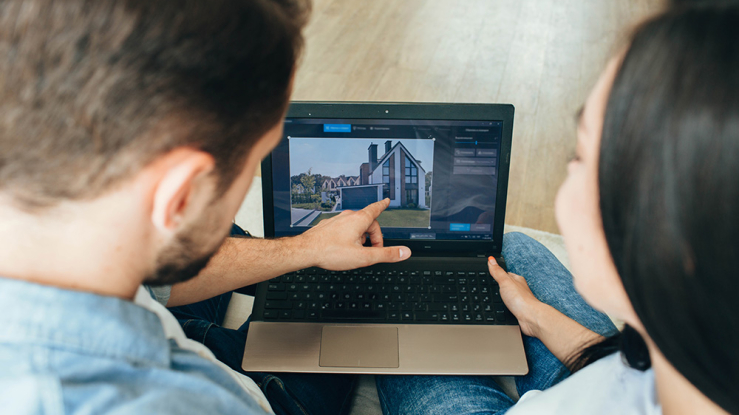 Couple pointing at real estate on laptop screen.