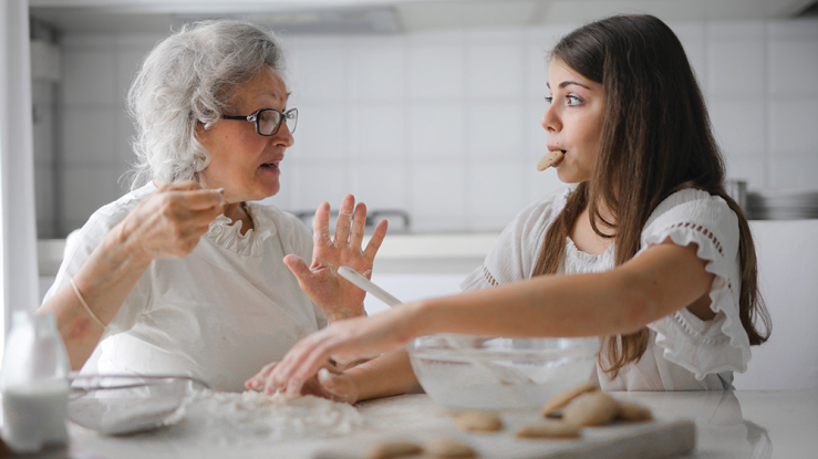 Older woman and teenage granddaughter make cookies.