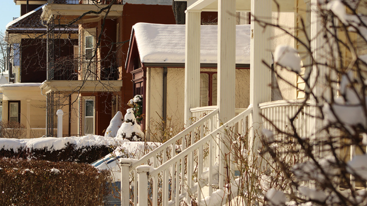 Snowy front porch and houses in the background.