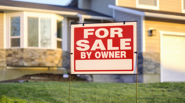 For-sale sign in yard of small home.