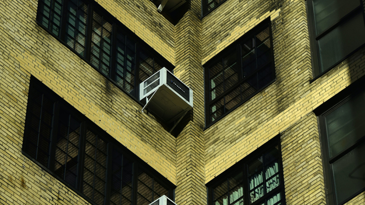 Air conditioners in apartment building windows.