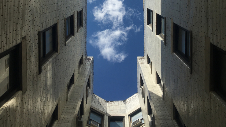 View of the sky looking up through the courtyard of an apartment building.