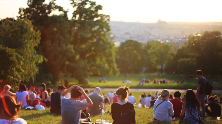 Group of young people sitting on hill overlooking city.