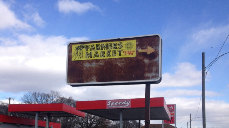 Advertisement for Brightmoor’s farmers market, in between a vacant field and a gas station.