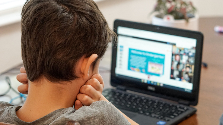Young boy staring at laptop screen at home.