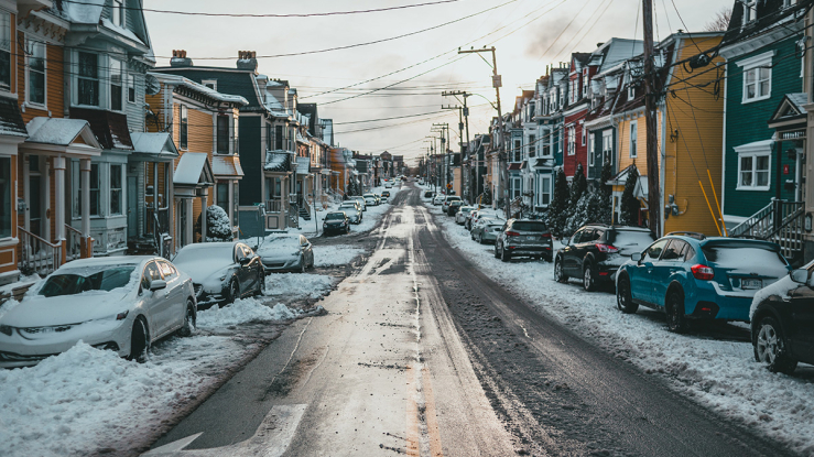 Snowy residential street with small homes.