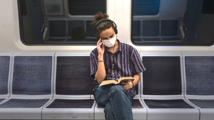 Man sitting and reading on a subway train.