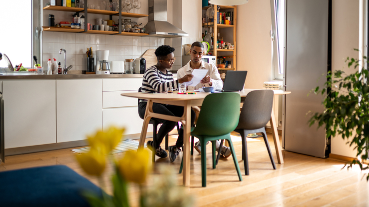 Two people reviewing bills at kitchen table.