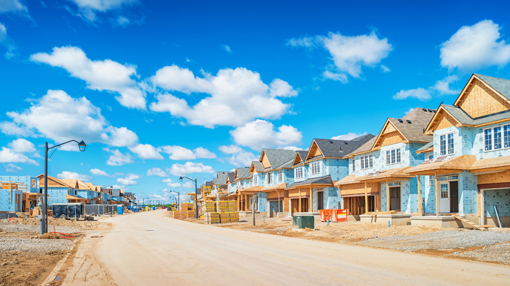 Row of homes under construction along a road.