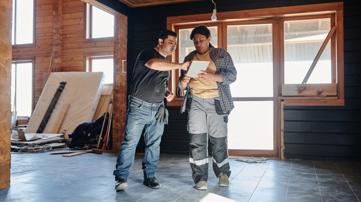 Two people examine plans for a remodeling project