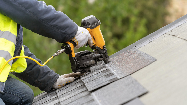 Person installing new roof on house.